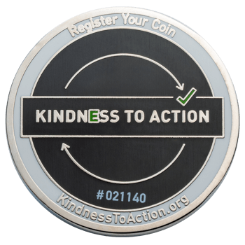 Kindness To Action challenge coin featuring a black textured center, circular arrows with a green checkmark, and a white border.