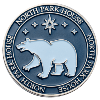 Round North Park House challenge coin featuring a light blue polar bear and stars on a dark blue enamel background with silver trim.