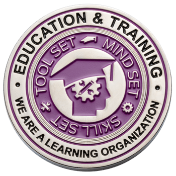 Circular silver challenge coin with purple enamel featuring a graduation cap icon and 'Education & Training' text.