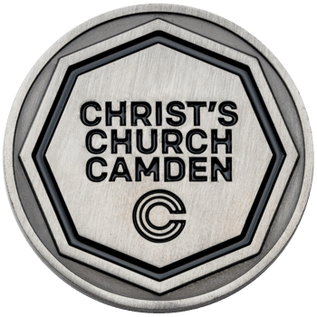 Antiqued silver challenge coin featuring Christ's Church Camden text and a circular C logo inside a recessed heptagon border with black enamel.